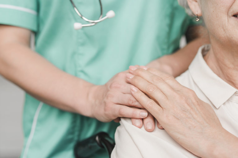 enfermeira segurando mão de paciente idosa