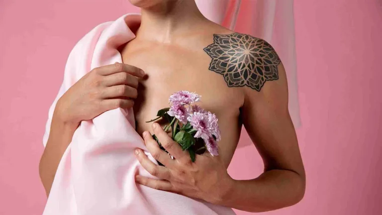 Câncer de mama triplo negativo está sendo representado por uma imagem do tronco de uma mulher segurando flores na cor rosa